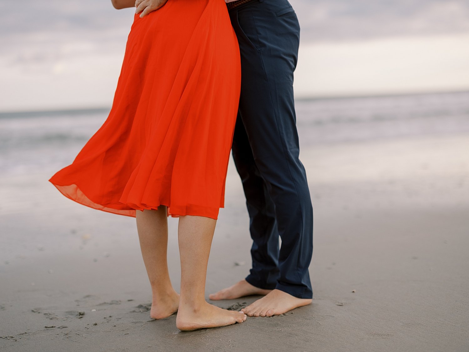 engaged couple hugs their toes touching on wet sand on beach in Ocean City NJ
