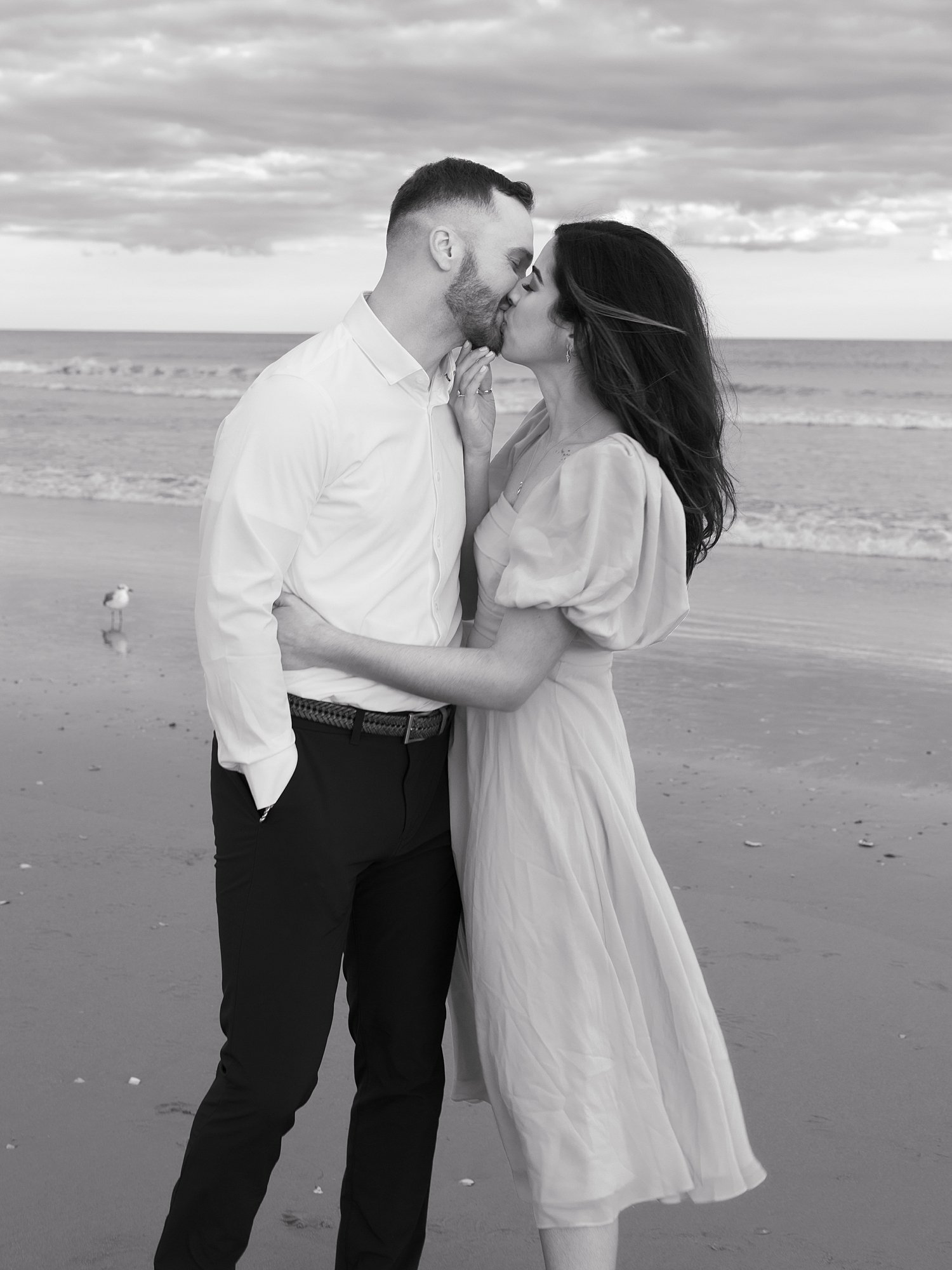 engaged man and woman kiss n beach at sunset in Ocean City NJ