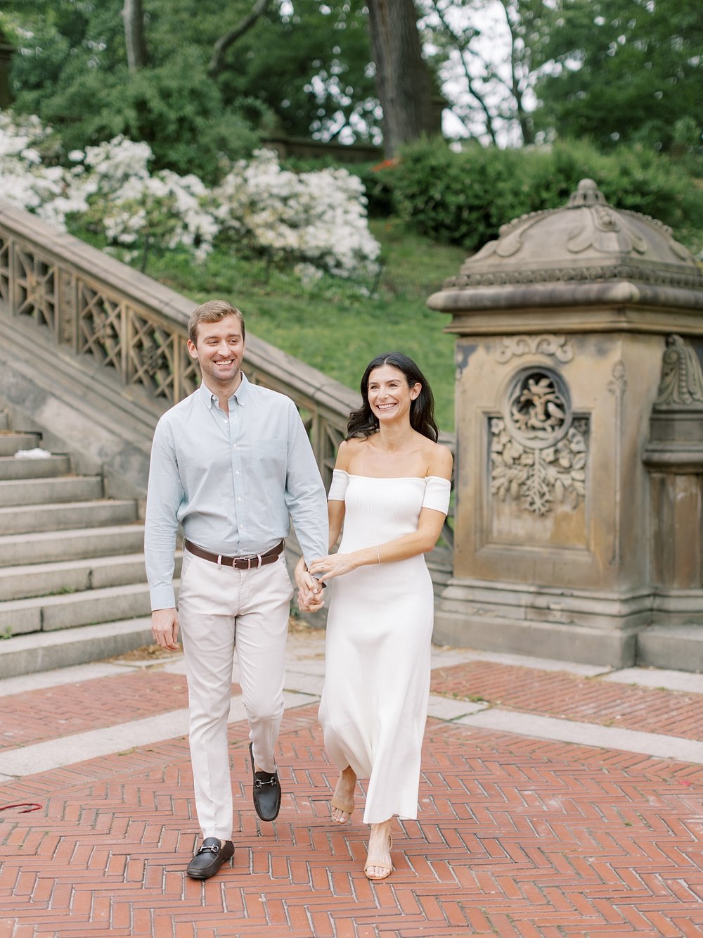 engaged couple holds hands walking near staircase inside Central Park