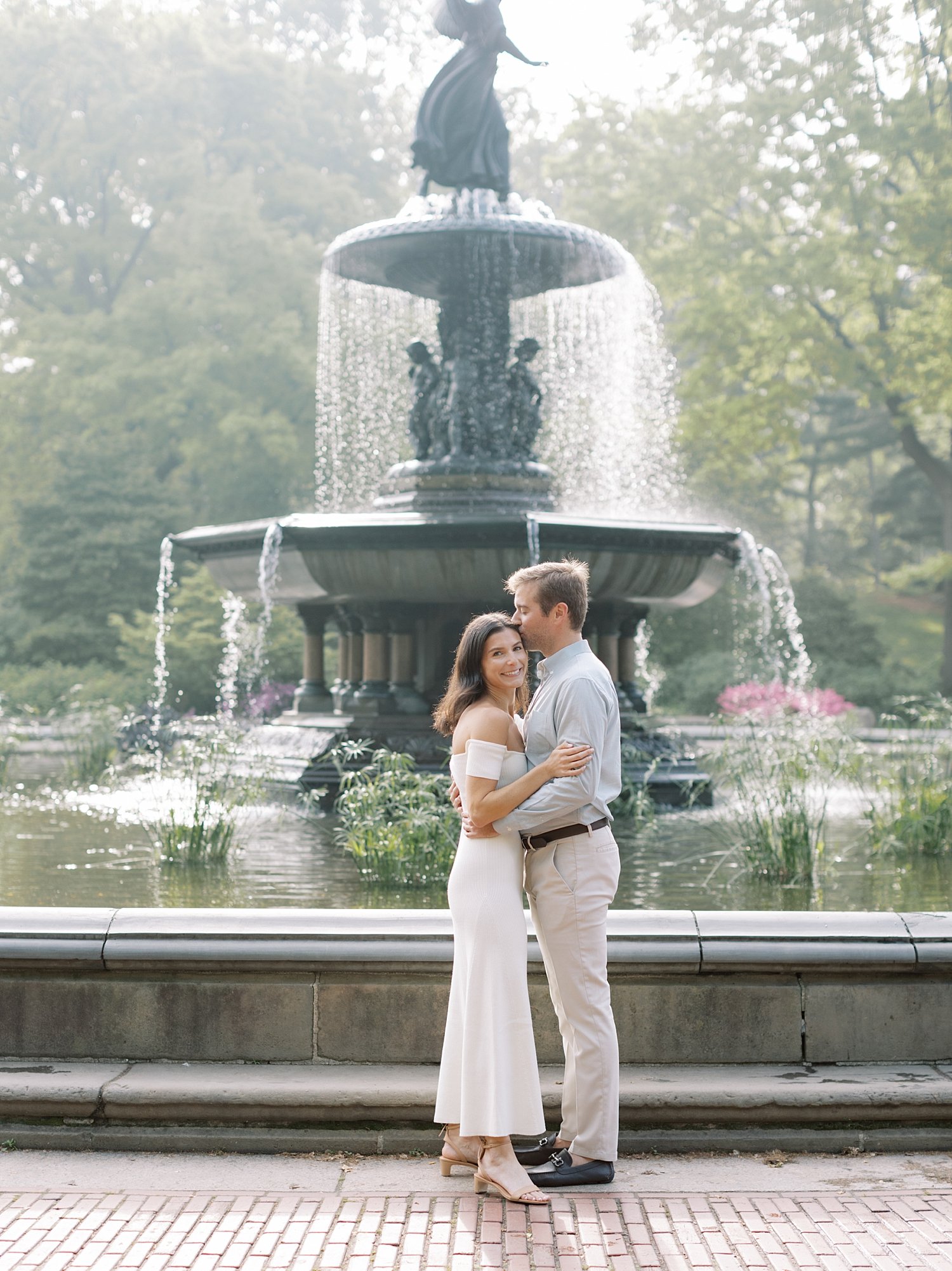man and woman hug in front of Bethesda Fountain in Central Park
