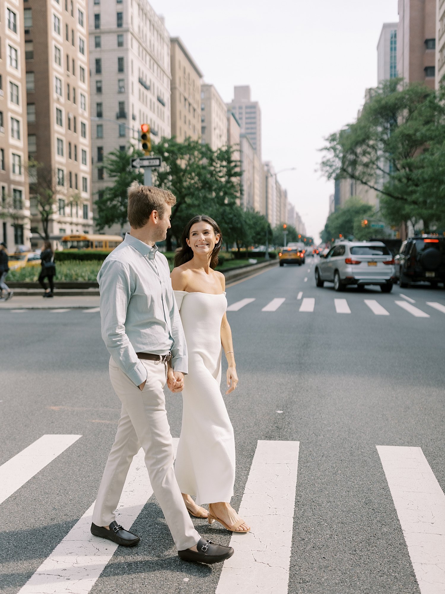 engaged couple holds hands crossing sidewalks on the Upper East Side in New York City