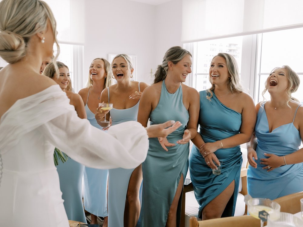 bride laughs with bridesmaids in blue gowns before wedding at the Rockaway Hotel