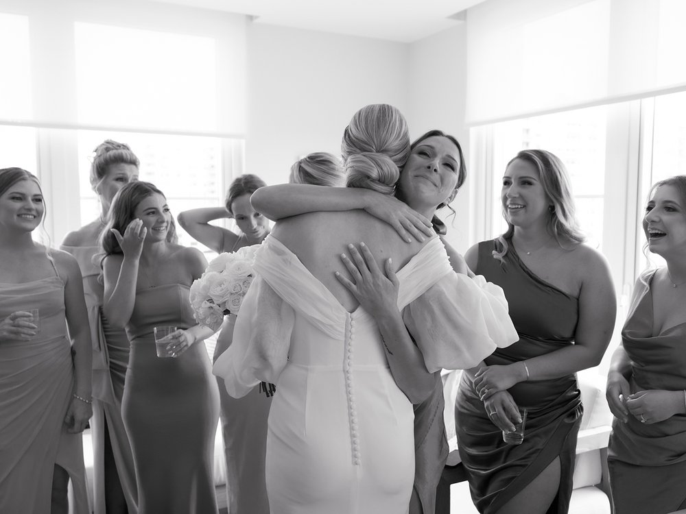 bridesmaid hugs bride after first look in suite at the Rockaway Hotel