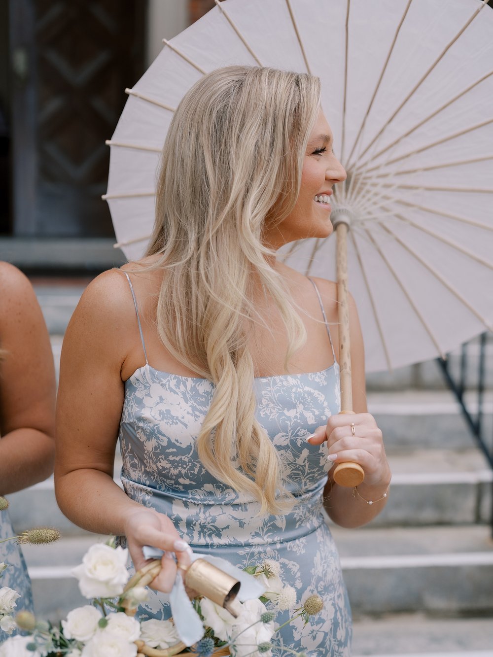 bridesmaid in blue and white gown holds white parasols on the Long Island boardwalk