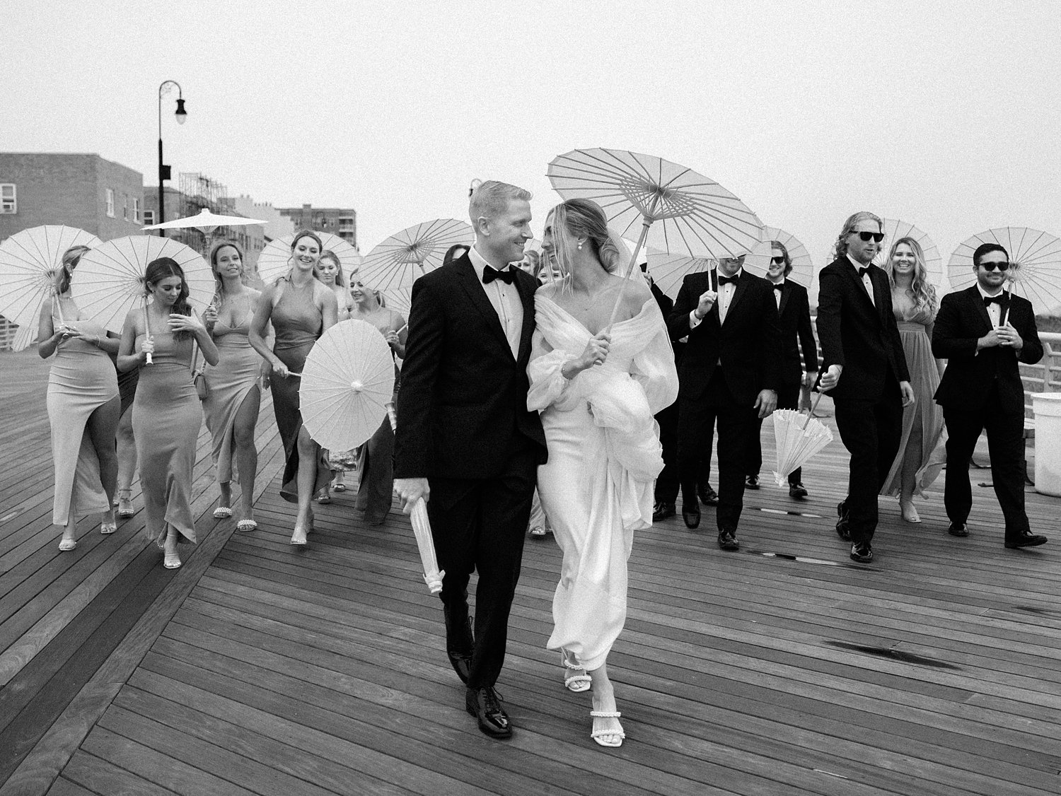 bride and groom walk with wedding party on the Long Island boardwalk