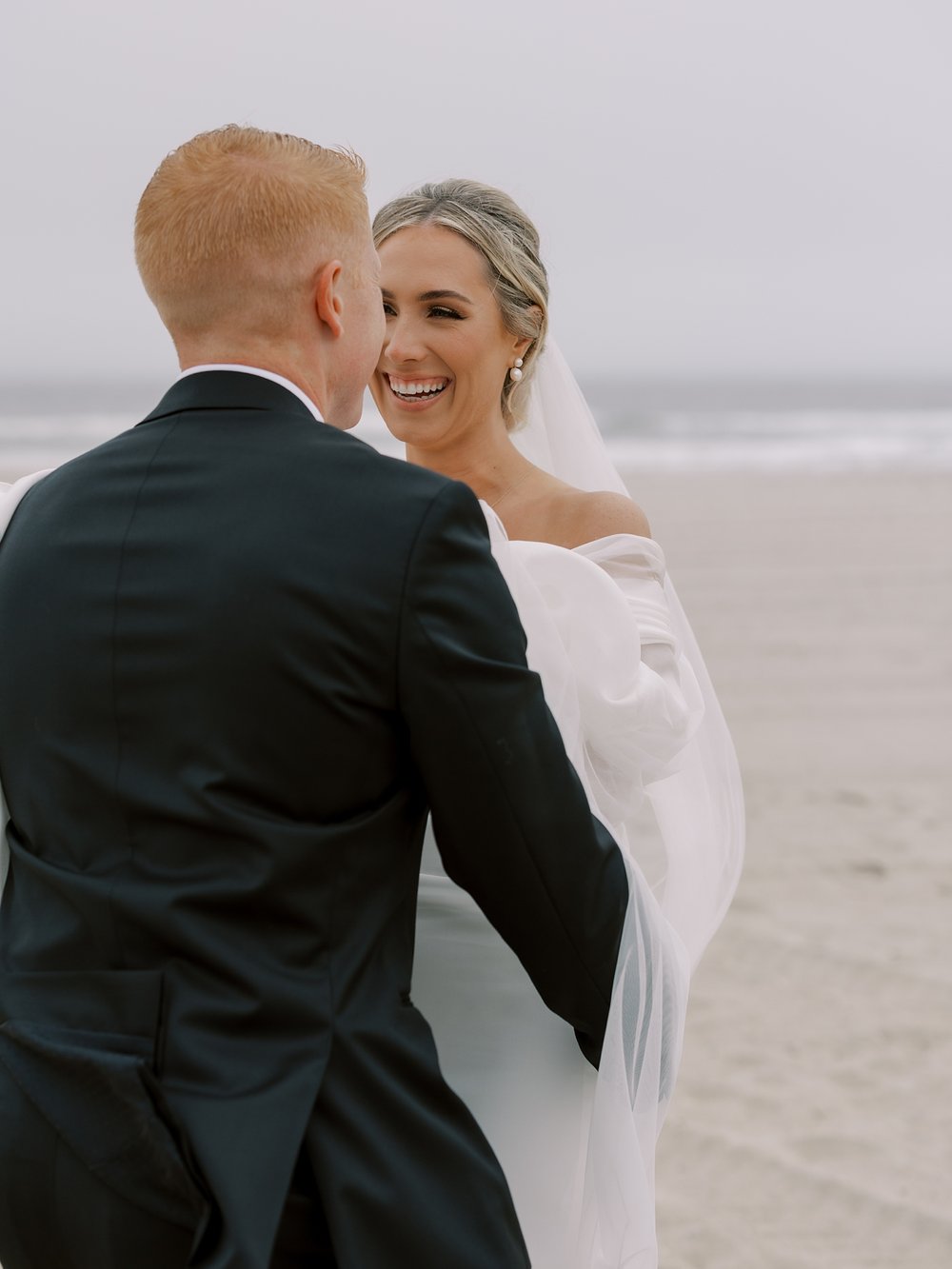 bride and groom laugh hugging on Long Island beach