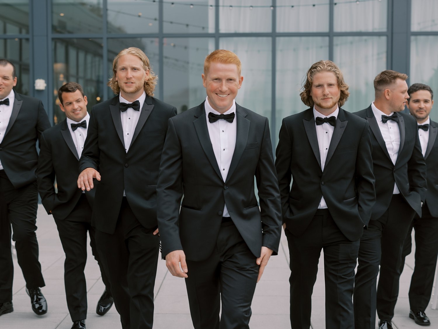 groom walks with groomsmen outside the Rockaway Hotel