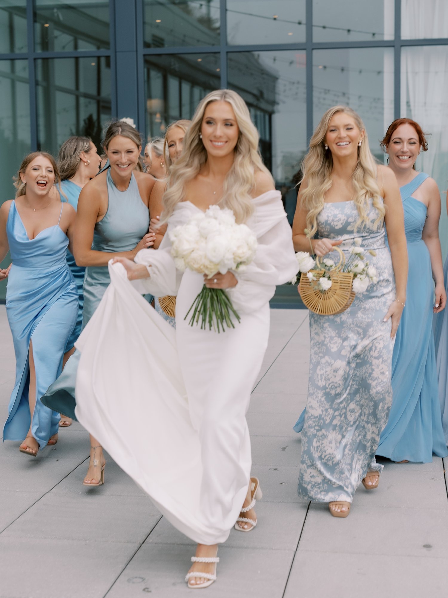 bride walks with bridesmaids in light blue gowns outside the Rockaway Hotel