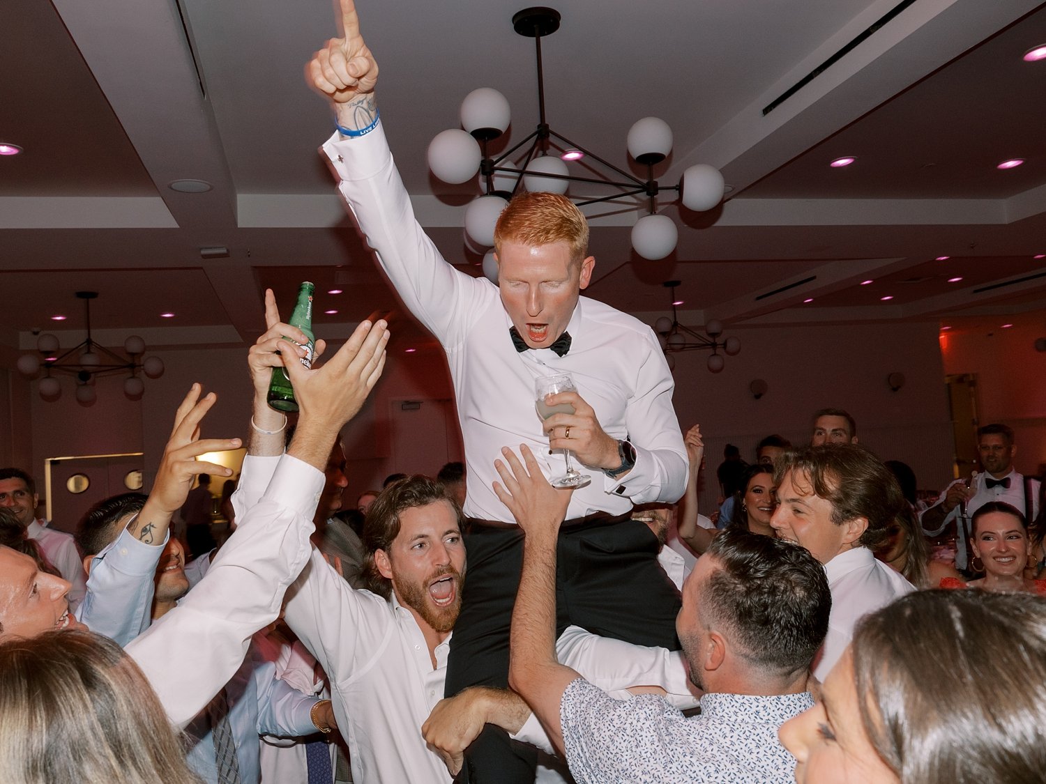 groomsman lift up groom on his shoulders  during Long Island beach wedding reception