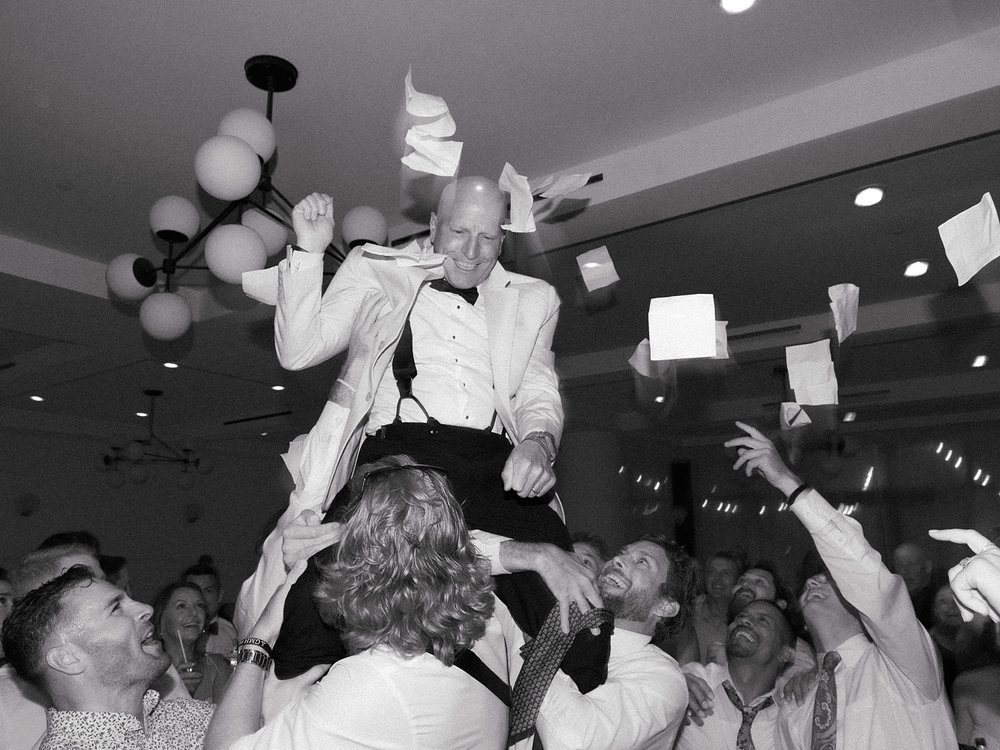 guests lift up father during Long Island beach wedding reception