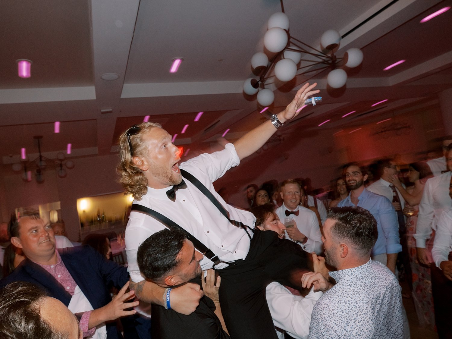 groomsmen lift up groomsman during Long Island beach wedding reception
