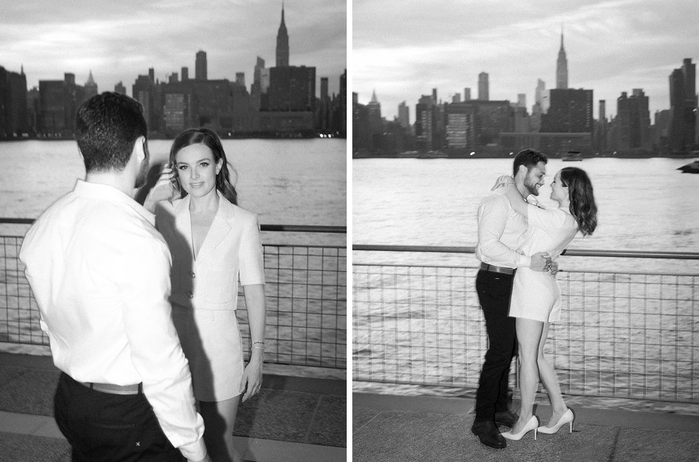 black and white portrait of couple hugging in front of NYC skyline in Greenpoint Waterfront Park