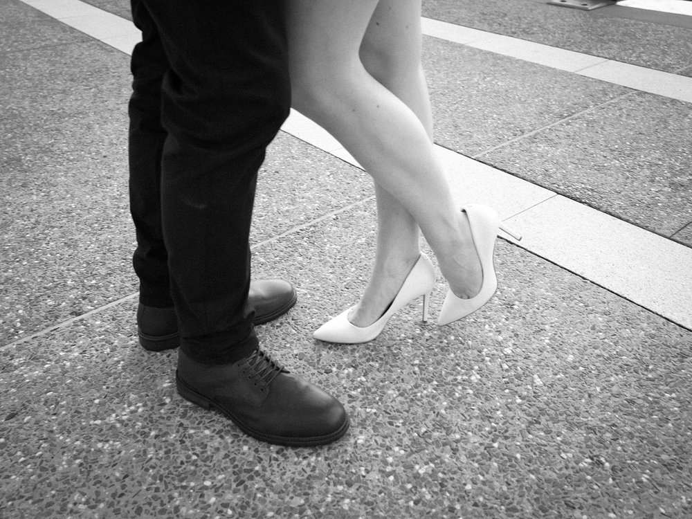 woman in white heels stands toe to toe with man in black shoes 