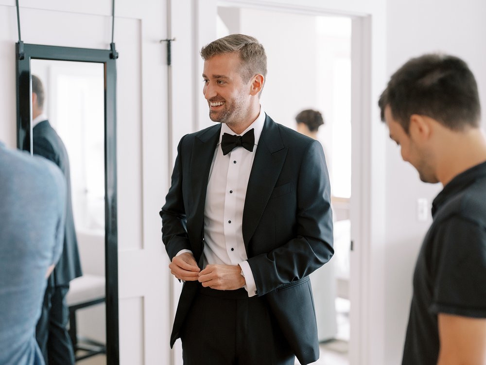 groom in tux jacket laughs with groomsmen at The Country Club of New Canaan