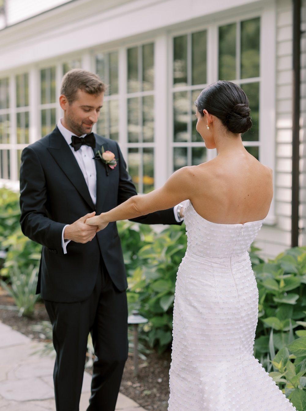 groom looks at bride's wedding dress during first look outside The Country Club of New Canaan