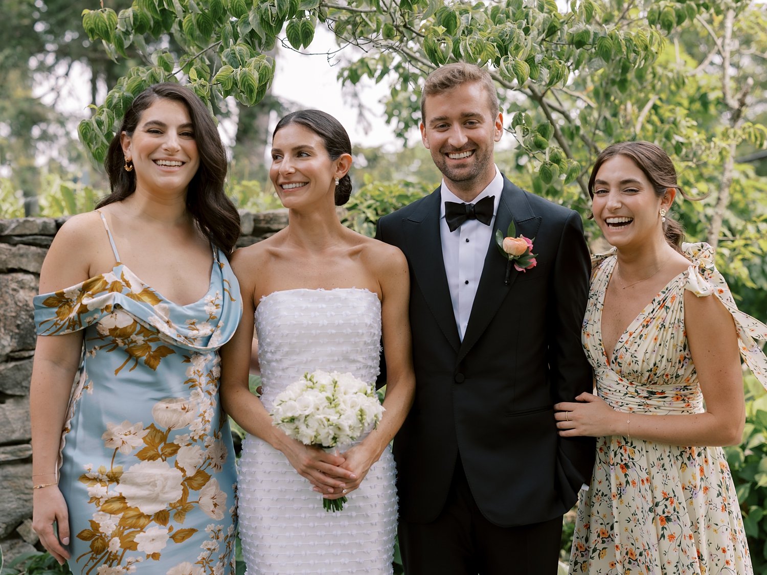 bride and groom smile with two bridesmaids in floral gowns