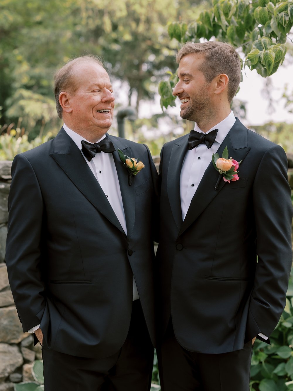 groom grins at father in suit jacket standing in the gardens at The Country Club of New Canaan