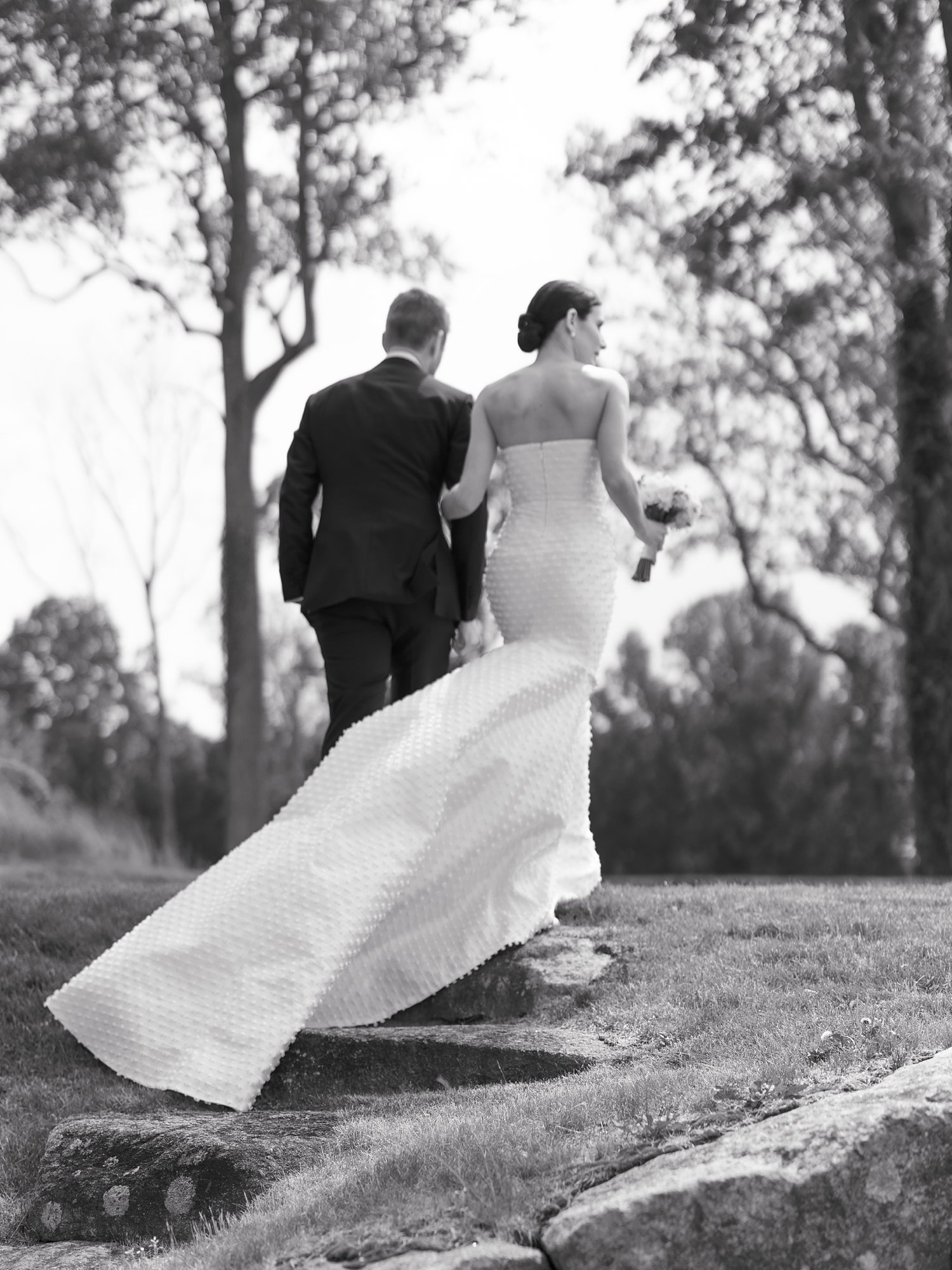 black and white photo of bride and groom holding hands walking up hill at The Country Club of New Canaan