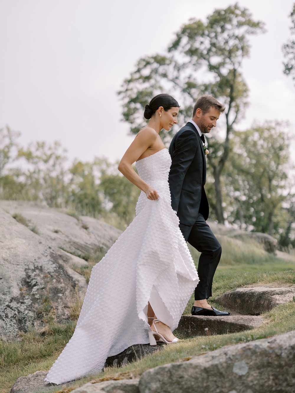bride and groom hold hands walking up rocks at The Country Club of New Canaan