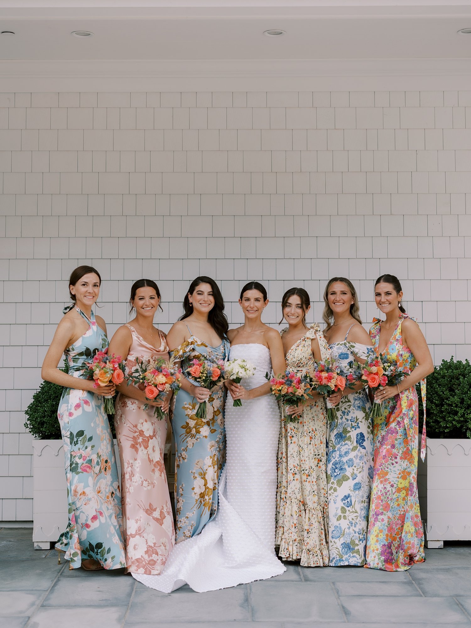 bride stands with bridesmaids in mismatched floral gowns for New England wedding