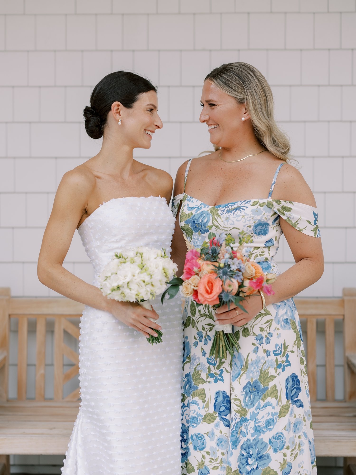 bride smiles at bridesmaid in blue and white flower gown