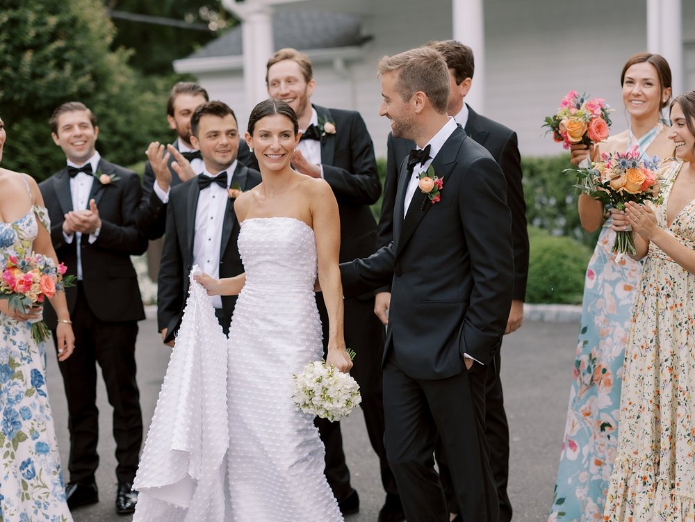 bride poses with bridesmaids in mismatched floral gowns for New England wedding