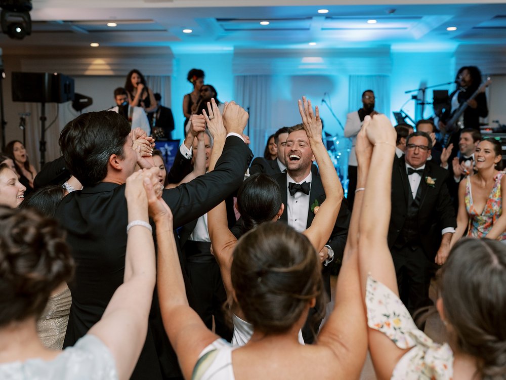 wedding guests dance with hands in the air at New Canaan wedding reception