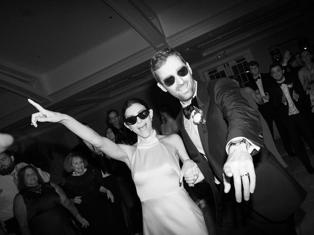 newlyweds dance together wearing sunglasses 