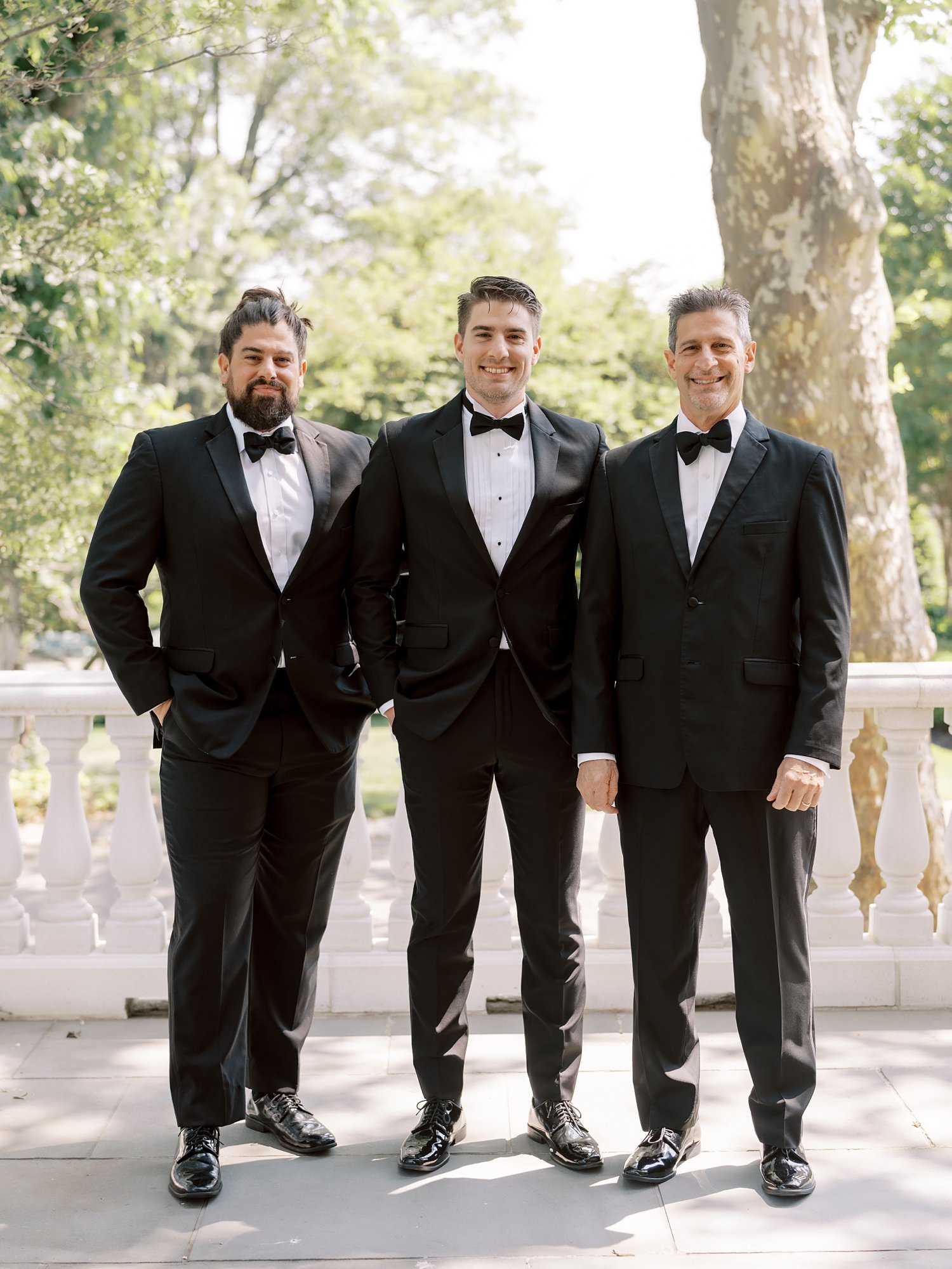 groom stands on patio with black tux at the Ashford Estate