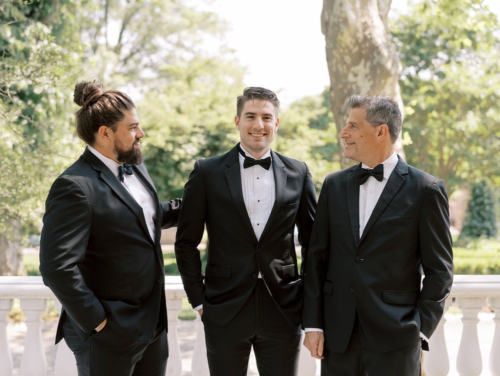 groom laughs with two groomsmen on patio at the Ashford Estate