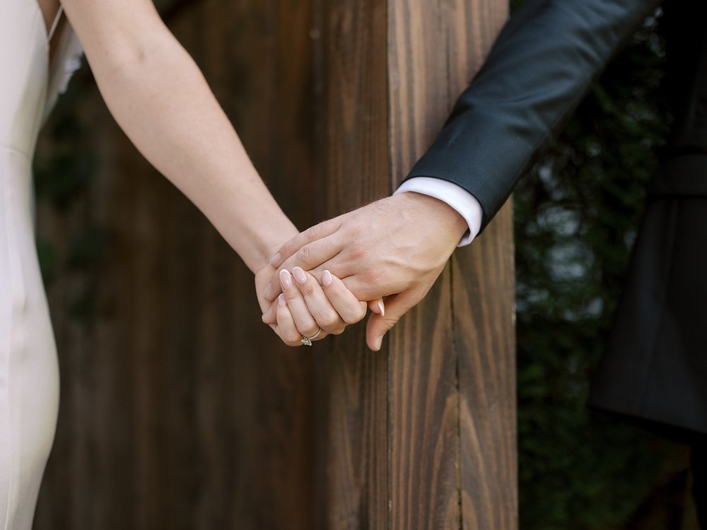 bride and groom hold hands around wooden gate at the Ashford Estate