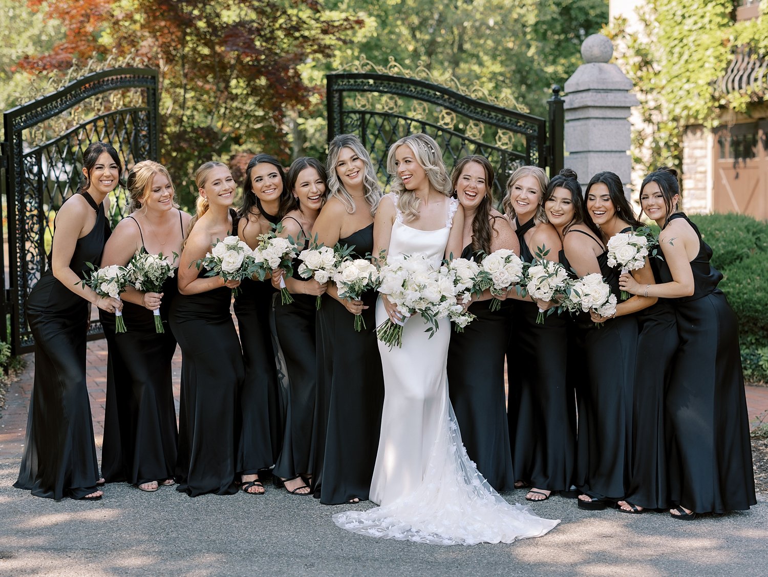 bride and bridesmaids pose in black gowns outside the Ashford Estate