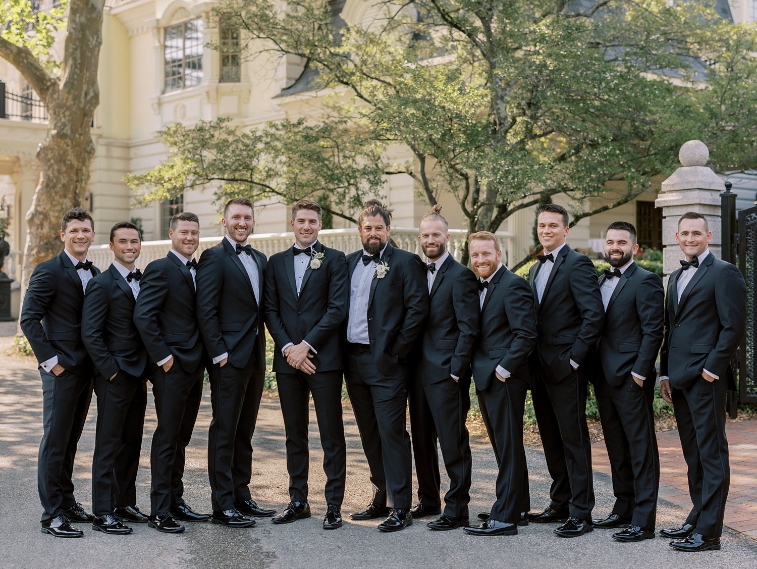 groom stands with groomsmen in black suits at the Ashford Estate