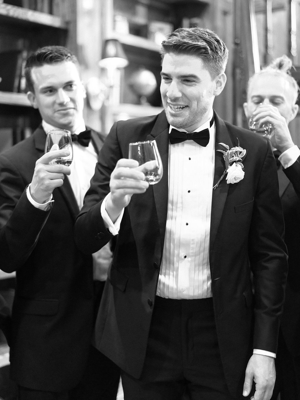 groom and groomsmen toast with whiskey glasses
