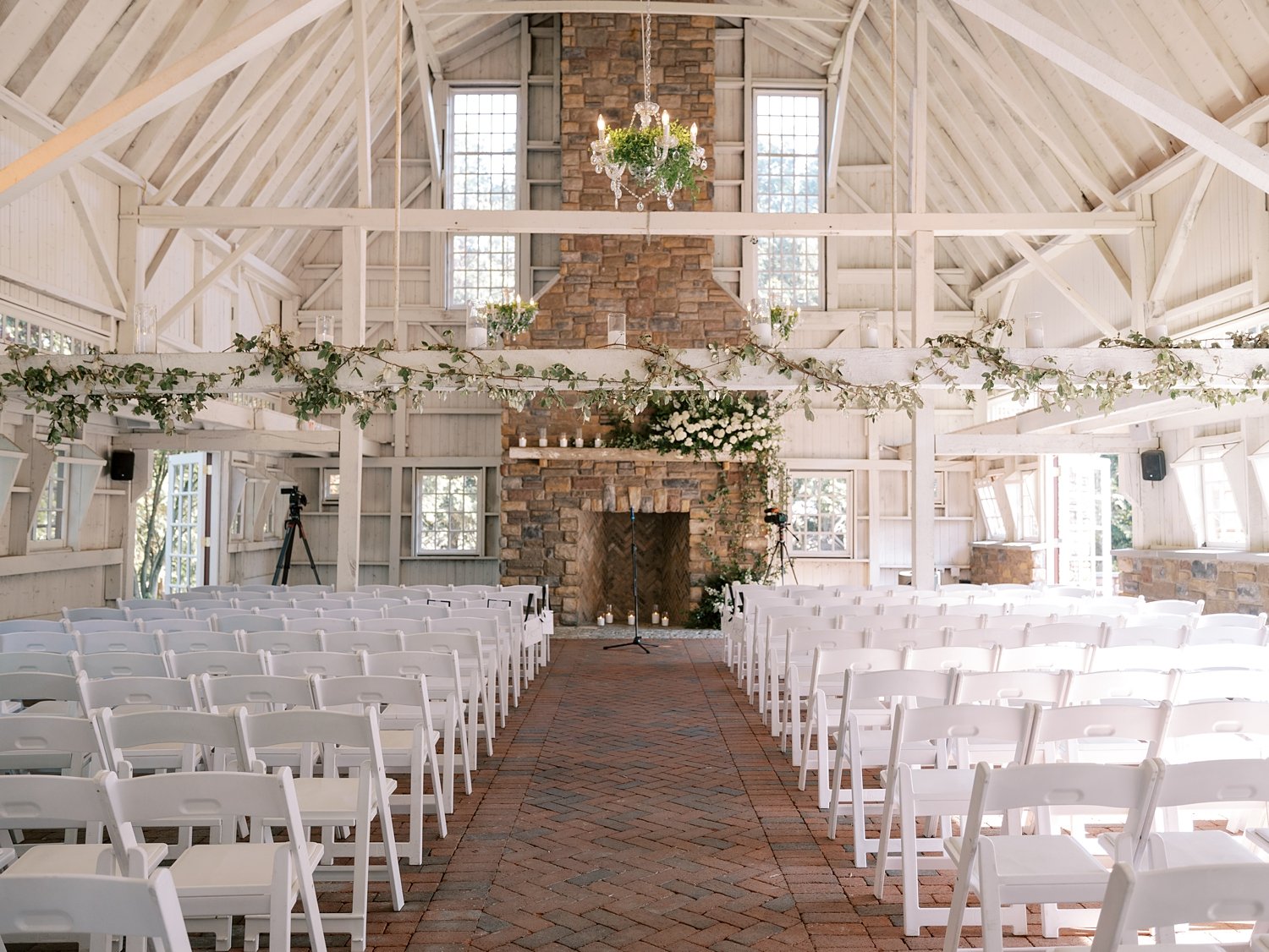 wedding ceremony inside barn at the Ashford Estate with white flowers and greenery on mantle