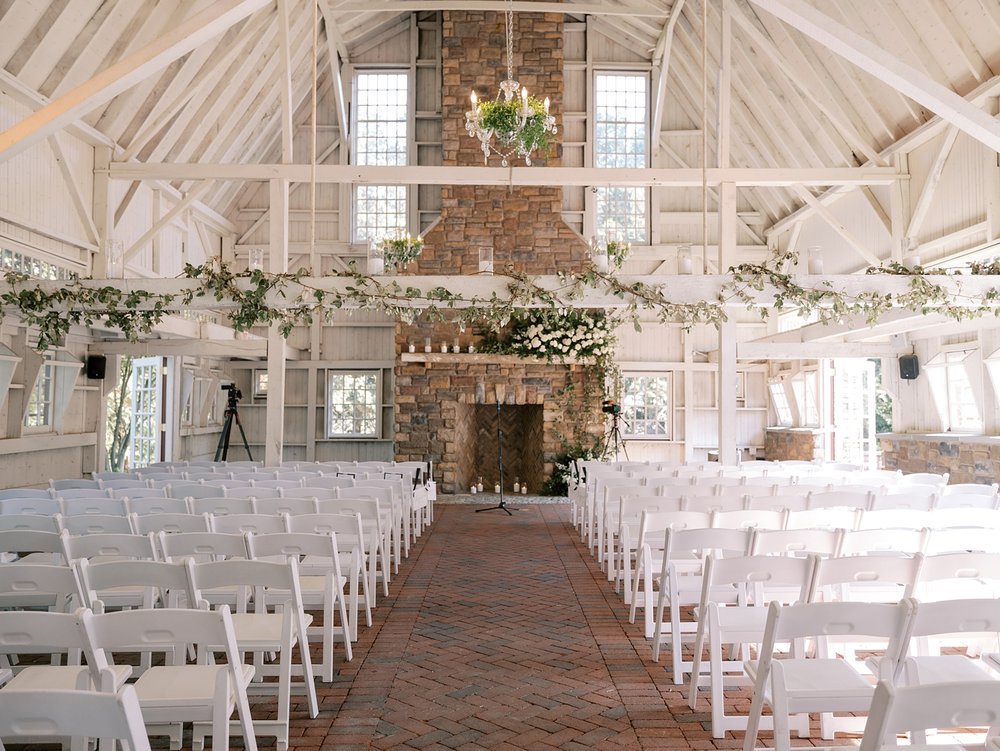 wedding ceremony inside barn at the Ashford Estate with white flowers and greenery on mantle