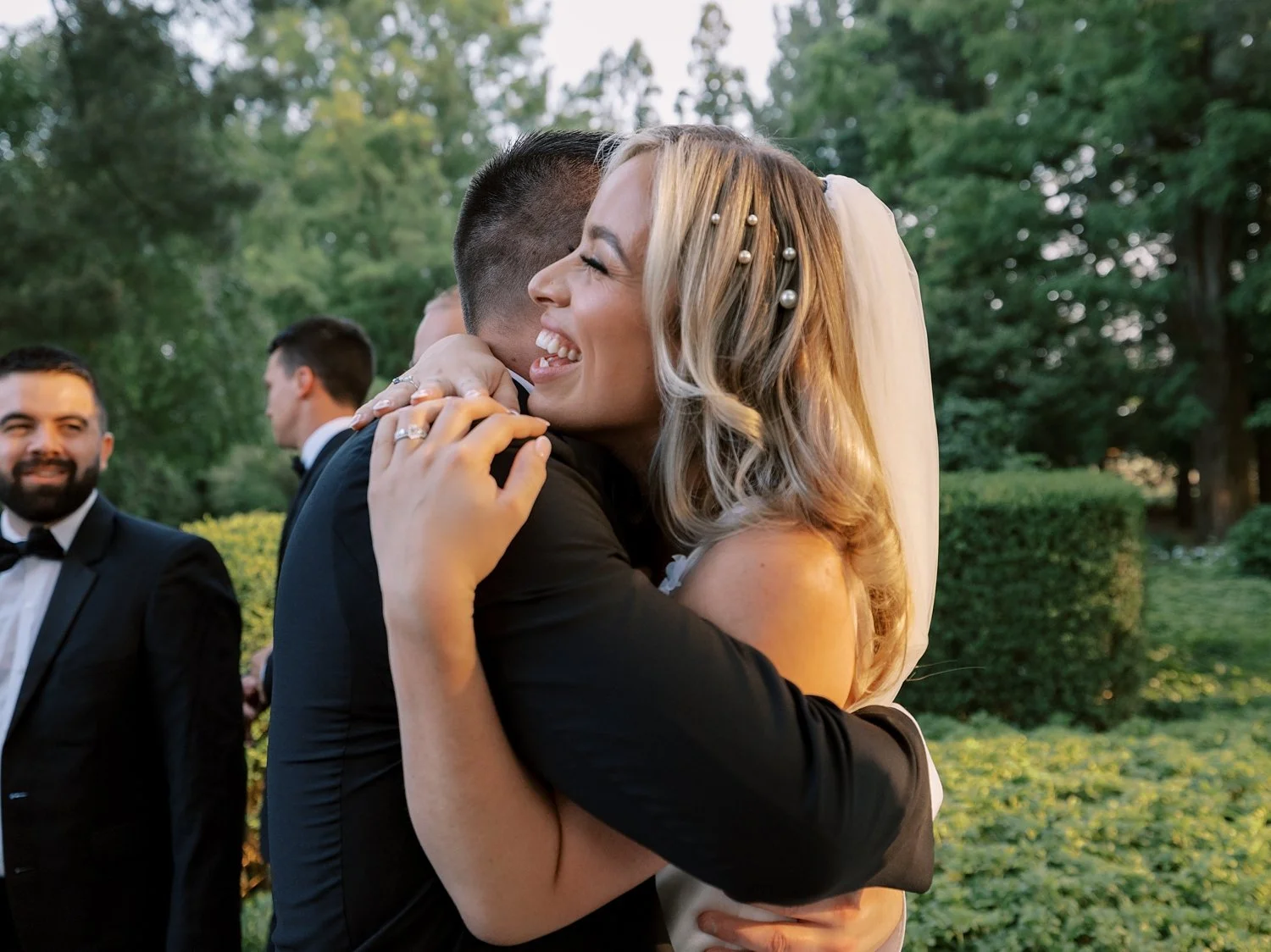 bride hugs groomsman during wedding day 