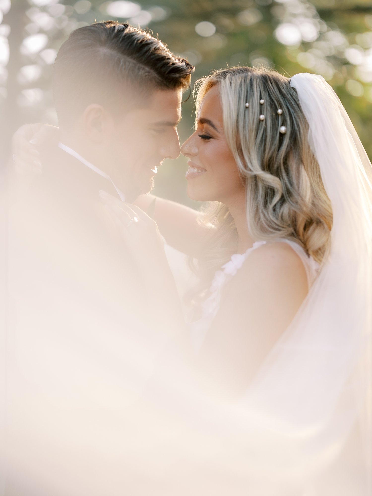 bride and groom hug leaning together with bride's veil in front of them