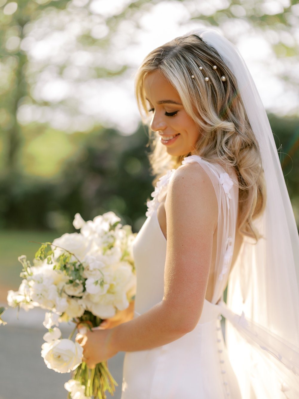 bride looks down at white bouquet in front of belly at the Ashford Estate