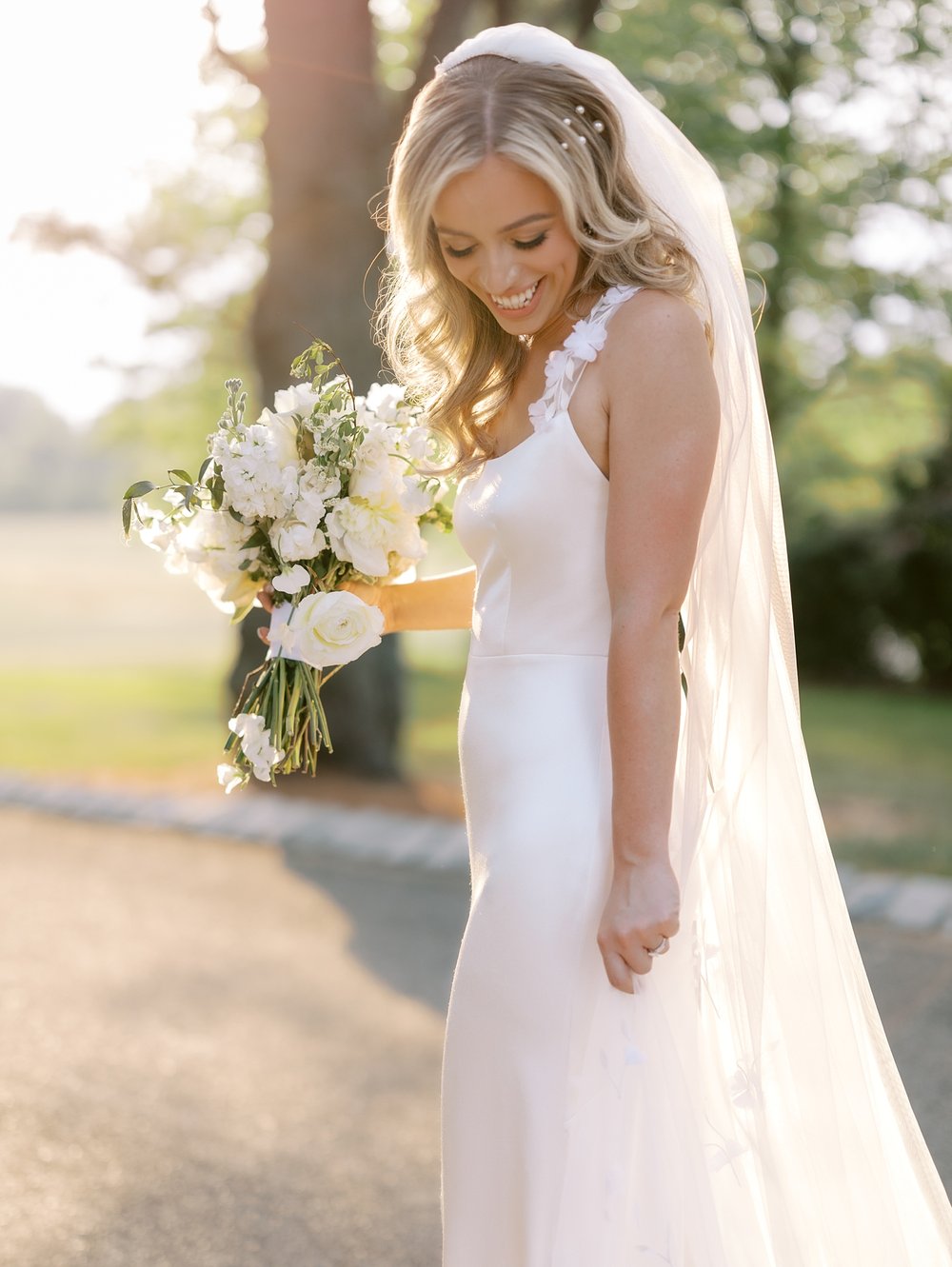 bride looks down while holding bouquet of white flowers outside the Ashford Estate