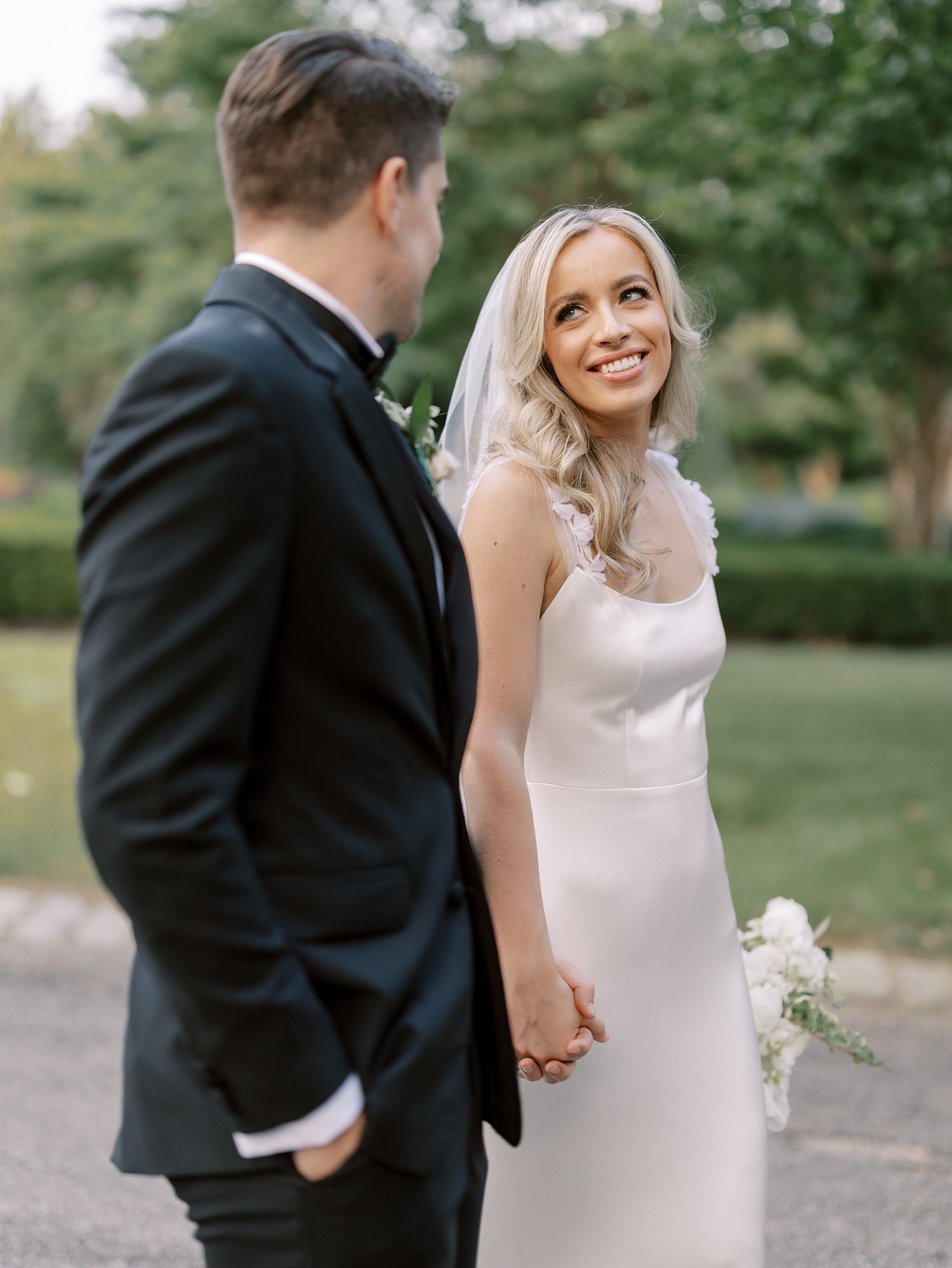 bride and groom hold hands smiling at each other outside the Ashford Estate