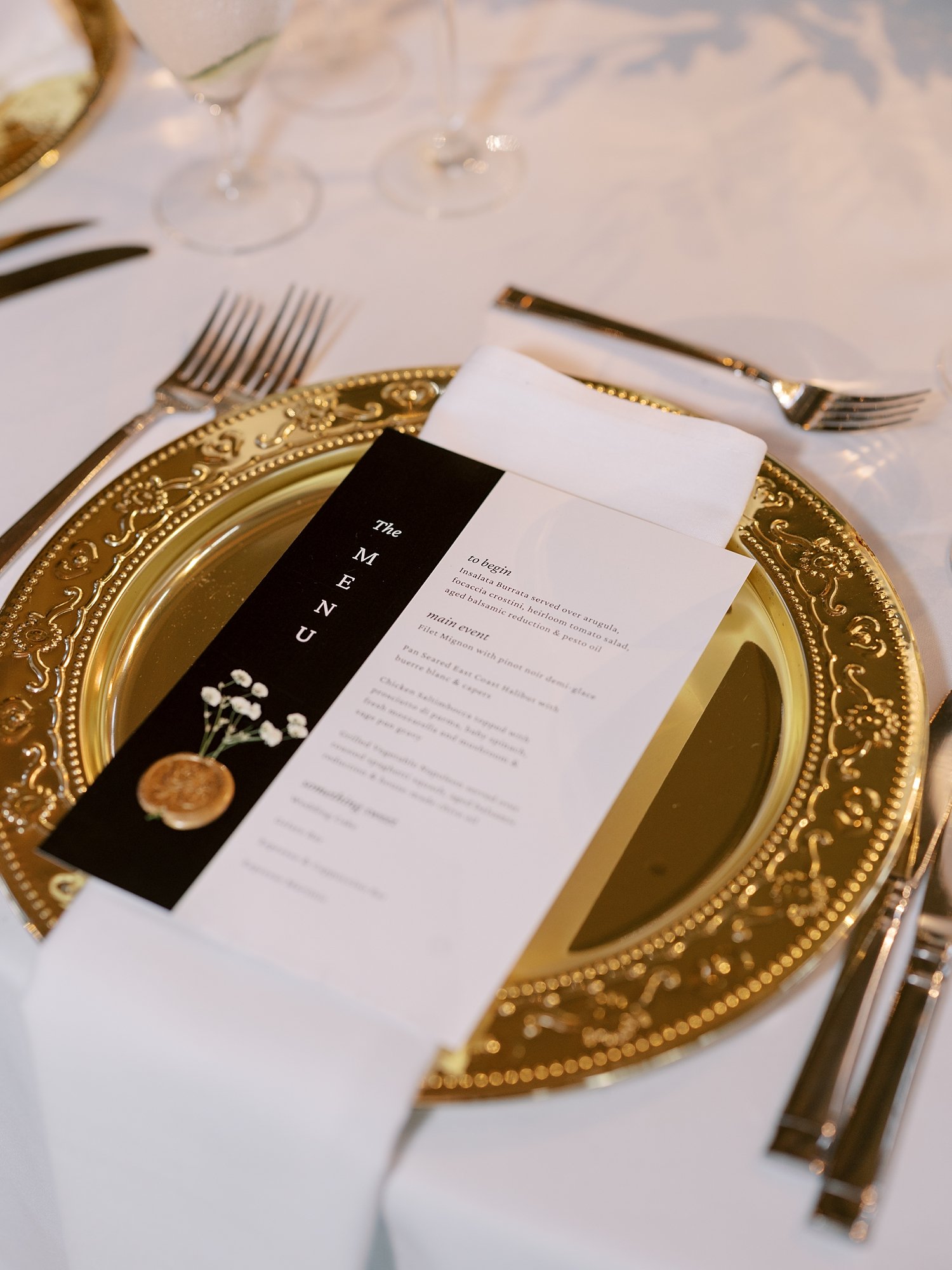 place setting for classic wedding reception with gold charger and black and white menu at the Ashford Estate