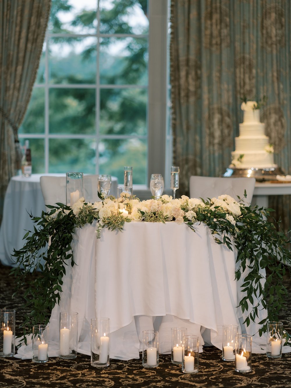sweetheart table with greenery draping down table and candles 
