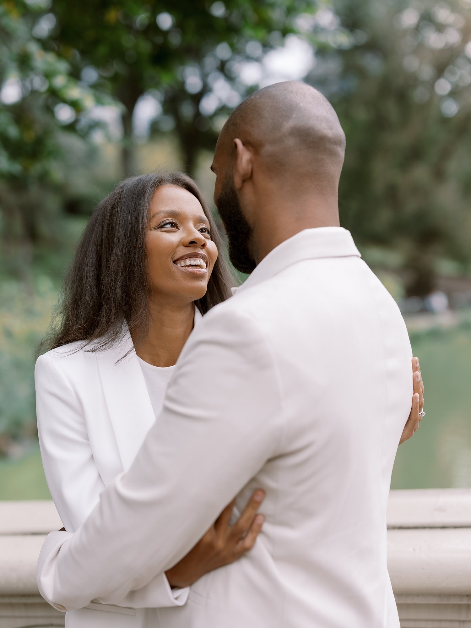 woman in white suit hugs husband during Central Park anniversary portraits 