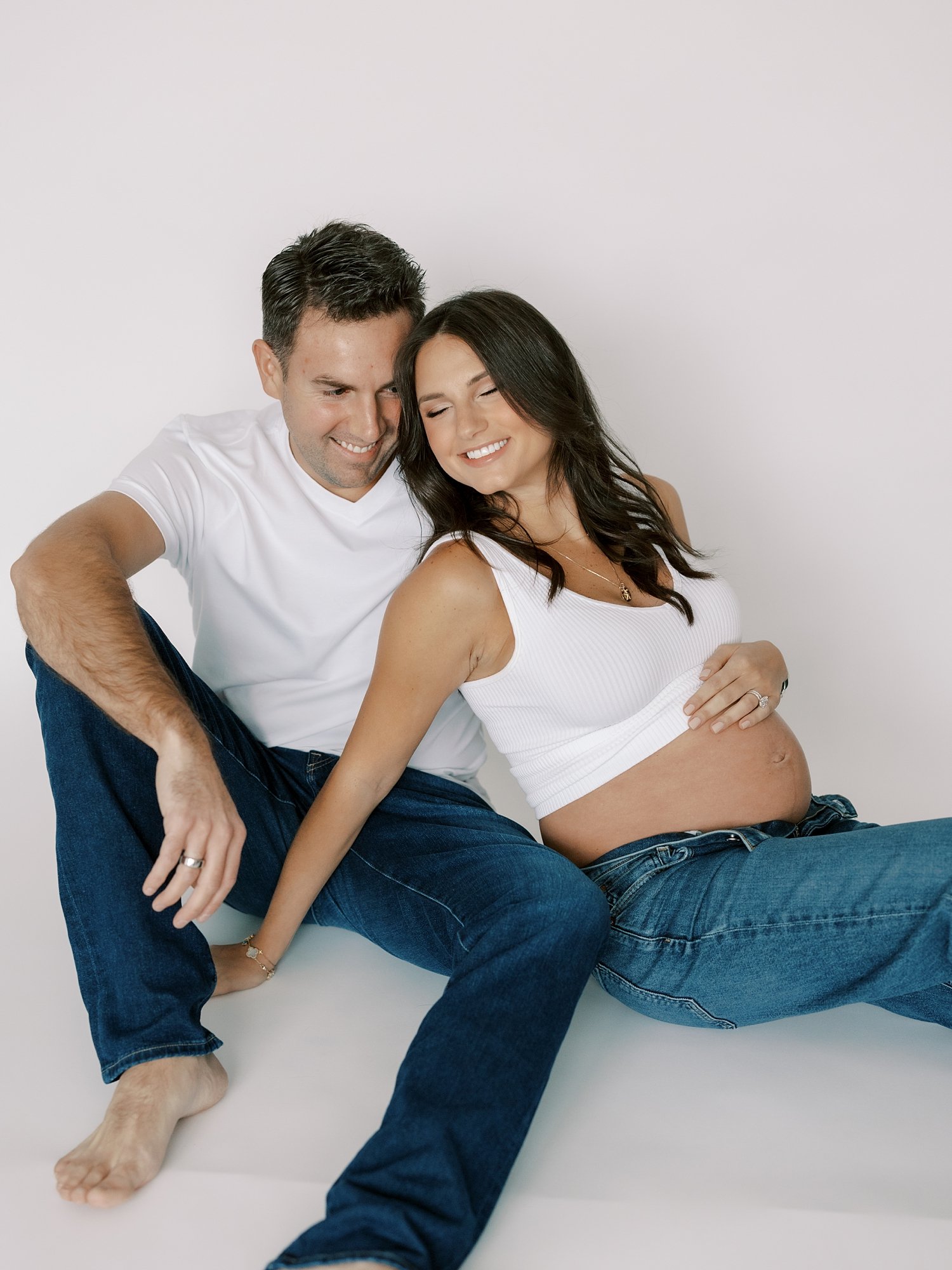 married couple leans together during studio maternity portraits in New York City