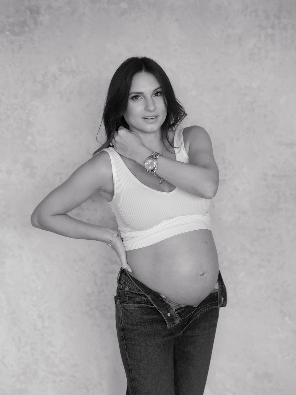black and white portrait of expecting mom wearing jeans and white bra during studio maternity portraits in New York City