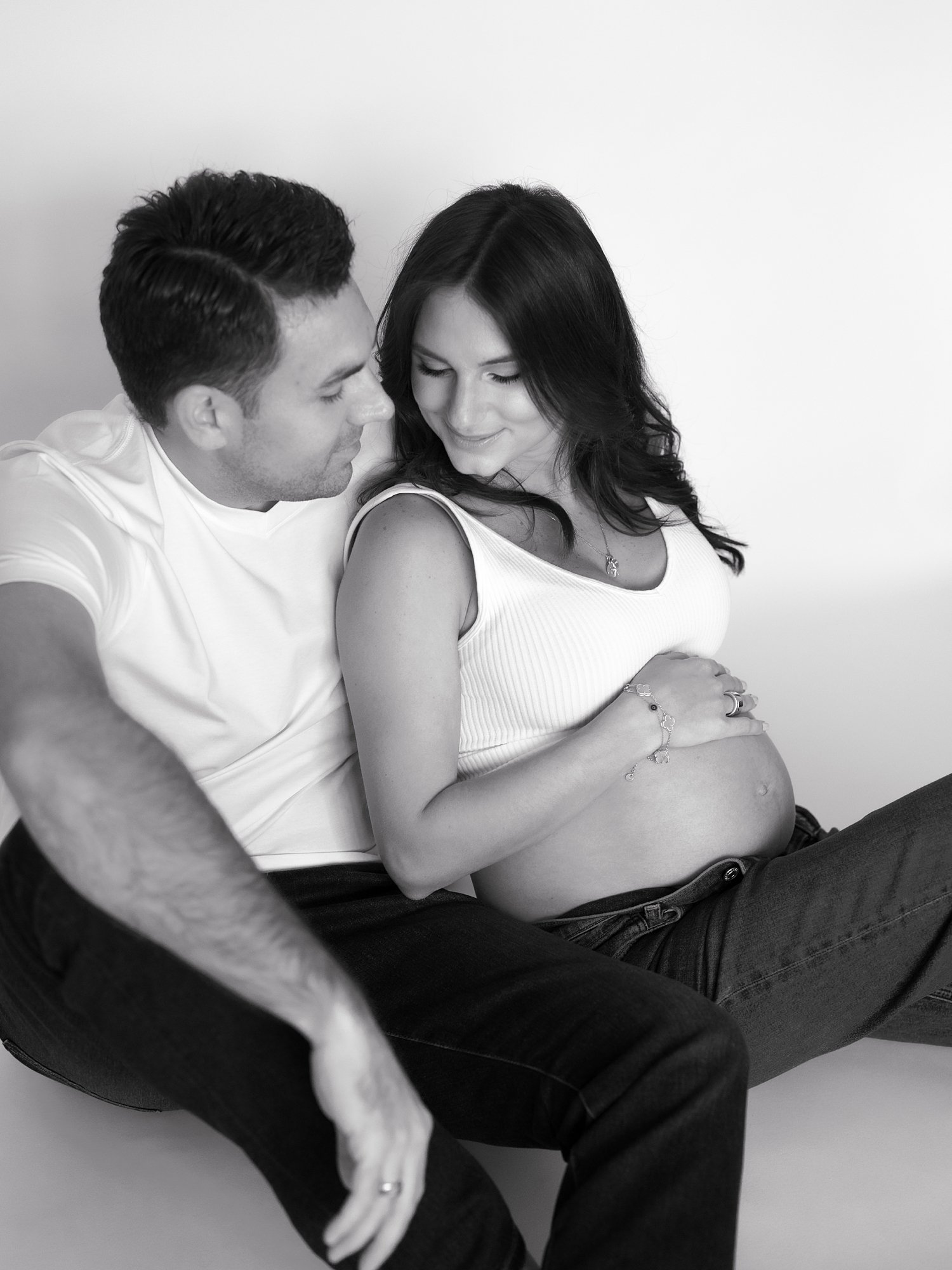 married couple sits together during studio maternity session in Greenwich 