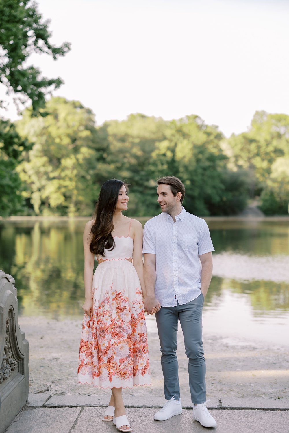 engaged couple holds hands in front of lake in Central Park