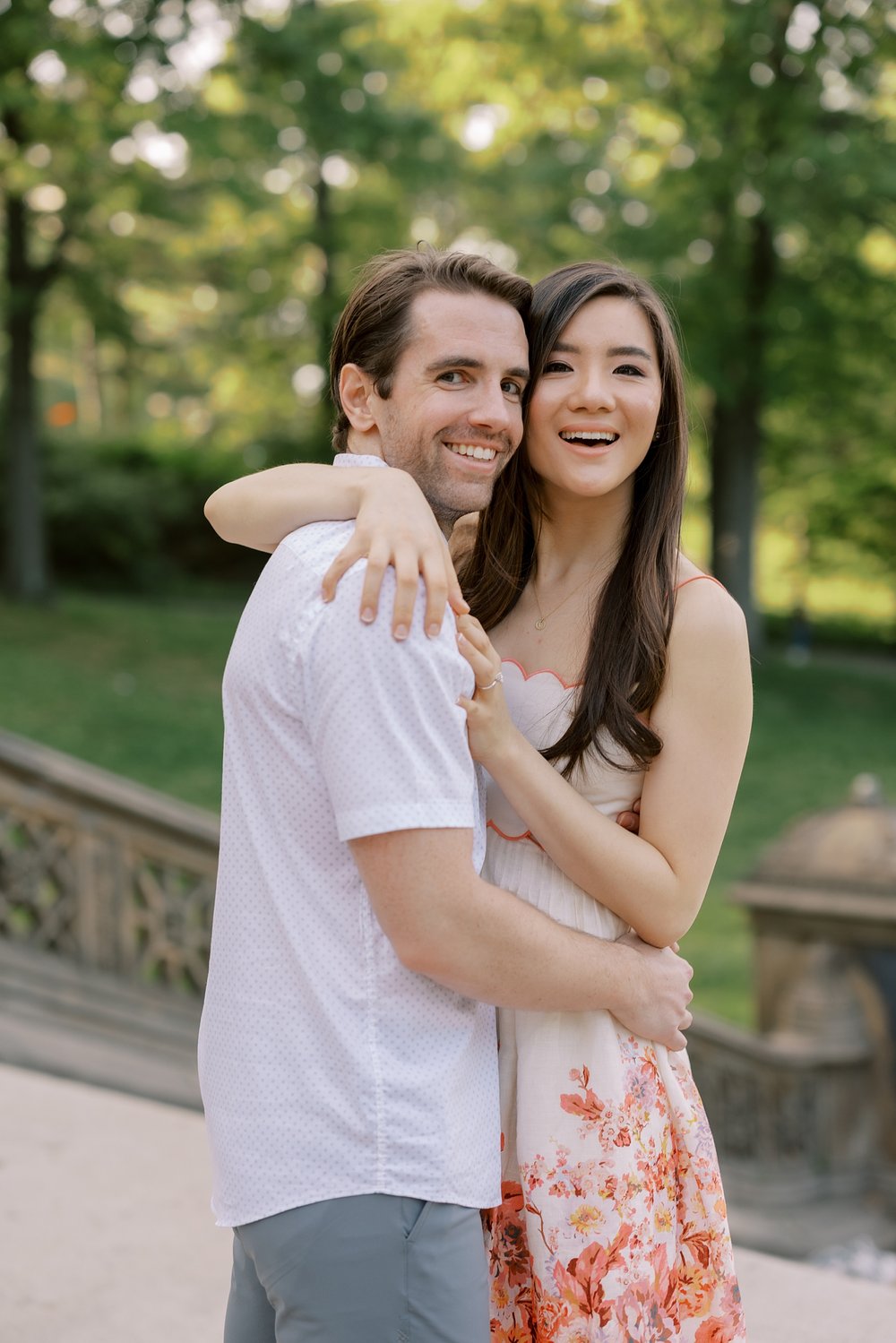woman hugs man around neck during spring engagement portraits in Central Park