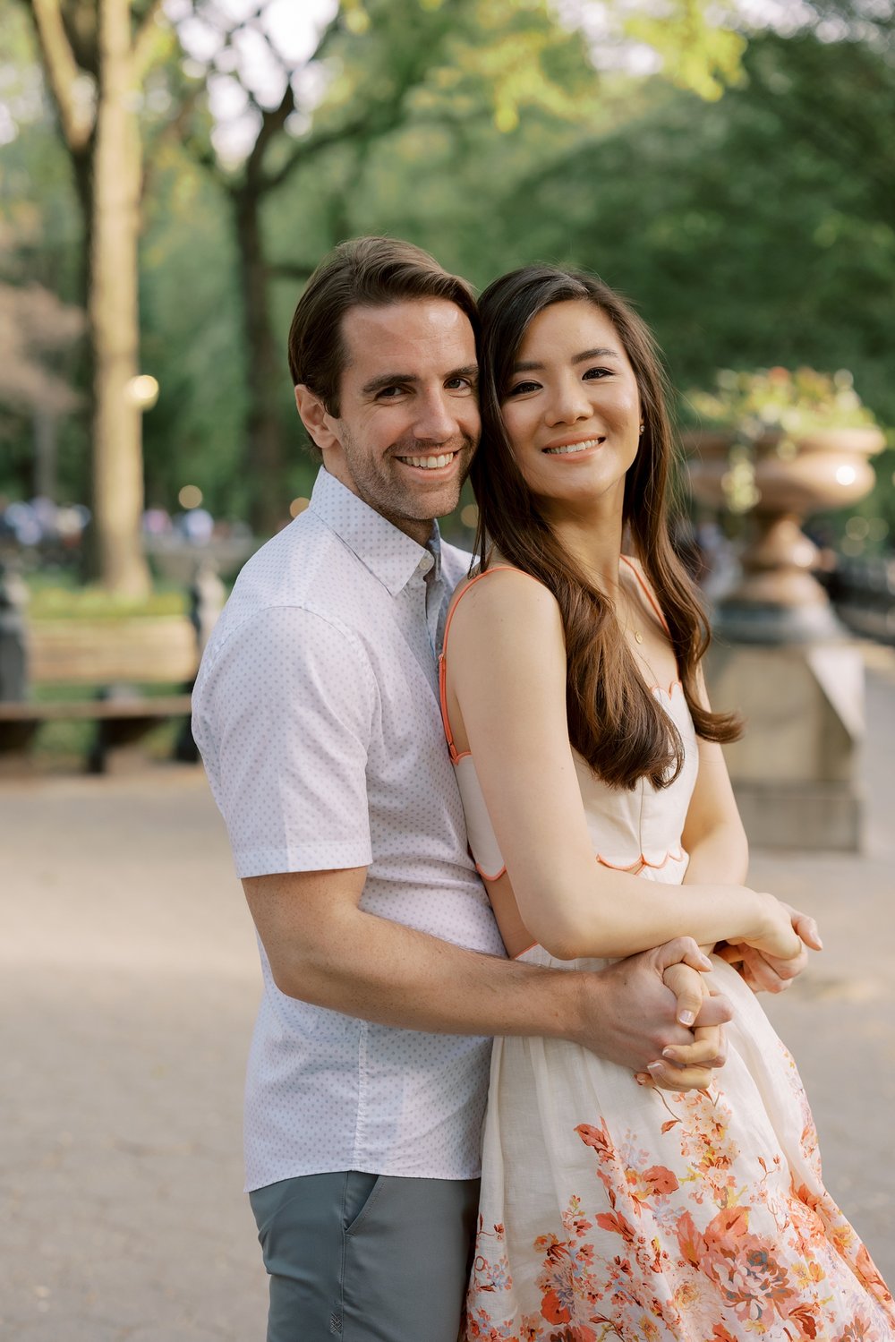 man hugs woman from behind during spring engagement portraits in Central Park